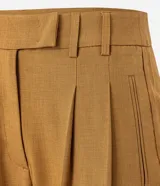 Pantalón de sastrería corte recto confeccionado en crepé, con pliegues delanteros y cintura con detalle cruzado. Presenta un diseño estructurado y elegante.