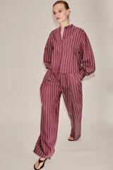 Camisa de cuello subido y manga larga con puños anchos, confeccionada en tejido satinado con diseño de rayas verticales.