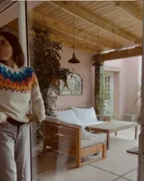 Sweater de punto tejido a mano con diseño nórdico en el canesú, combinando tonos crudo, marrón y negro. Presenta cuello redondo y mangas largas, con una textura suave y abrigada.