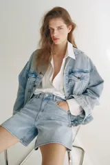 Short de media pierna en denim de algodón levemente elástico, de tiro alto con diseño de cinco bolsillos y cierre con botón.