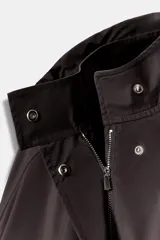 Cazadora de cuello subido con capucha ajustable, manga larga con puños elásticos y bajo elástico. Cuenta con bolsillos delanteros y cierre frontal con cremallera oculta y botones a presión.