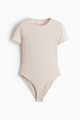 Body de manga corta en microfibra de color beige, con escote redondo, ajuste ceñido al cuerpo y cierre de broches a presión en la entrepierna.