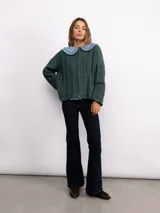 Sweater de punto oversize en color bordó con destellos de lurex. Presenta un diseño acanalado vertical, cuello redondo y mangas largas con terminaciones acampanadas y bordes ondulados.