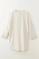 Vestido color beige con cuello mao, mangas 3/4 abullonadas y cierre parcial con botones.