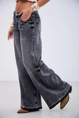Pantalón de jean estilo wide leg en color negro con efecto lavado. Presenta un corte holgado, tiro medio y costuras reforzadas a lo largo de las piernas, con un ruedo deshilachado y desgastado.