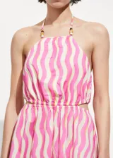 Vestido midi de algodón con diseño estampado de ondas verticales en tonos rosa y crema. Presenta cuello halter con detalle de abalorios, espalda descubierta, aberturas laterales tipo cut-out en la cintura y falda evasé.