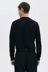 Buzo negro de punto fino con cuello redondo, mangas largas y remates acanalados en cuello, puños y bajo. Corte estándar.