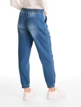 Pantalón tipo jogger de denim azul con efecto lavado. Presenta cintura elástica con cordón ajustable, bolsillos laterales y traseros, y puños elásticos en los tobillos.