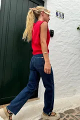 Pantalón de jean azul oscuro, de corte recto y tiro medio, con detalle de ruedo desflecado.