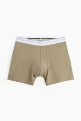 Pack de tres calzoncillos tipo trunk, confeccionados en punto elástico de algodón con tecnología Lycra® Xtra Life™. Incluye un par en color caqui, uno gris jaspeado y uno verde oliva, todos con cintura elástica blanca con franjas grises y verdes.