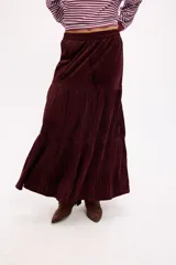 Falda larga de color negro con textura símil terciopelo, presenta un diseño con volados y detalle de tachas en la cintura.