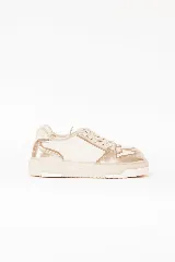 Championes estilo urbano con combinación de cuero metalizado en tono oro y off white, con detalles de costuras pespunteadas, cordones al tono y suela de goma chunky.