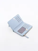Billetera de cuero sintético color celeste, con diseño tipo sobre, cierre principal superior y bolsillo frontal con cierre.