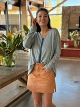 Sweater gris de tejido fino de viscosa, con escote en V y detalle de tira de cuero ovino aplicada en el centro.