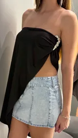 Top negro de diseño asimétrico tipo strapless, con drapeado lateral y detalle de hebilla metálica plateada.