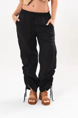 Pantalón holgado negro de lino con cintura elastizada y cordones ajustables en los laterales de las piernas.