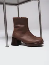 Botas de caña corta en gamuza color beige, con plataforma y taco cuadrado de madera oscura. Presentan cierre lateral interno.