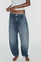 Jeans de tiro medio y corte barrel con diseño de perneras curvadas, tiro medio, trabillas para cinturón y cinco bolsillos. Presenta lavado clásico y costuras pespunteadas decorativas en la parte delantera.