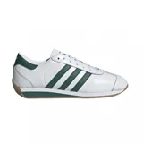 Championes adidas Country II de diseño clásico, color blanco con las icónicas tres tiras laterales y detalles en el talón en color verde. Presentan suela de goma color caramelo y entresuela blanca con una franja verde.
