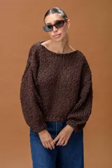 Sweater de tejido de punto grueso con textura trenzada y destellos de lurex, en color chocolate. Presenta un diseño oversize con cuello redondo amplio y mangas largas con puños ajustados.
