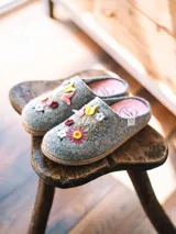 Pantuflas de fieltro color gris, abiertas en el talón, con delicados bordados florales multicolores en el empeine y detalle de trenza de yute en la suela.