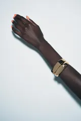 Pack de dos pulseras abiertas (tipo brazalete) de metal color dorado, con diseño rectangular y una pequeña aplicación de cristal o joya en un extremo.