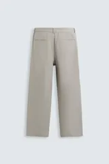 Pantalón de vestir color blanco hueso, de corte recto y tiro medio, con cintura elástica y cierre frontal de botón y cremallera. Presenta bolsillos frontales y bolsillos traseros de vivo.