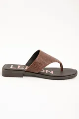 Sandalias de cuero color marrón, tipo ojota con taco bajo, tira ancha con textura trenzada y plantilla con inscripción de la marca.