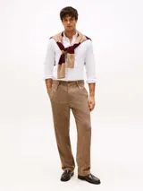 Camisa blanca de corte regular, confeccionada en tejido Oxford de algodón con un toque de elasticidad. Tiene cuello abotonado, mangas largas con puños abotonados y logo de Tommy Hilfiger bordado en el pecho.