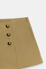 Shorts mini de tiro alto en color beige, confeccionados en mezcla de algodón, con doble hilera de botones metálicos dorados en la parte frontal y cierre lateral con cremallera oculta.
