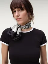 Remera baby tee negra de manga corta, ajustada al cuerpo, con ribetes blancos en el cuello redondo y los puños.