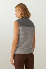 Chaleco de lana fina sin teñir con diseño acolchado en rombos y canesú en contraste. Cuenta con cuello alto, cierre frontal de cremallera y bolsillos laterales.