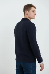 Cardigan tejido color azul marino, con cuello y solapa, cierre frontal de botones y bolsillos delanteros. Presenta un tejido de punto con textura.