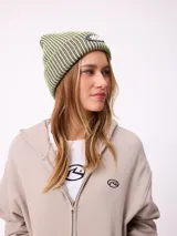Gorro tipo beanie de tejido acanalado con diseño a rayas verticales en tonos azul y gris. Presenta un parche frontal con el logo de la marca Rusty.