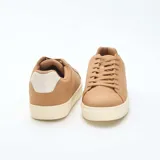 Zapatillas bajas para hombre de color beige, con cordones del mismo tono, suela de goma blanca y detalle en el talón.