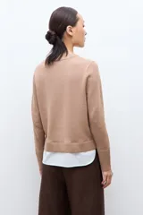 Sweater azul marino de manga larga con cuello redondo, combinado con una camisa celeste que se asoma por debajo.