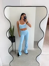 Conjunto deportivo compuesto por un top de breteles finos con ribetes blancos y un pantalón tipo semi oxford de tiro alto con tajos laterales en el ruedo.