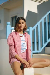 Camisa de calce relajado y silueta amplia con estampado cuadrillé en tonos rojo y blanco. Presenta cuello clásico, cierre frontal mediante botones y mangas largas.