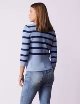 Buzo tejido de punto con diseño a rayas horizontales en tonos azul claro y azul marino. Presenta escote en V con una tapeta frontal decorada con botones metálicos y mangas tres cuartos.