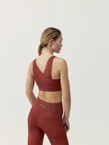 Top deportivo color ladrillo con estampado geométrico, de sujeción media-alta y tirantes cruzados en la espalda.