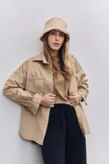 Camisa de pana color beige, con corte oversize, cuello clásico, bolsillos frontales y cierre con botones.