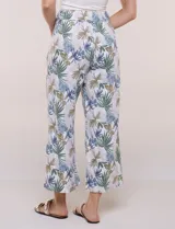 Pantalón crop de lino y rayón, con diseño wide leg de corte holgado, estampado tropical de hojas en tonos verde, azul y marrón sobre fondo blanco. Cuenta con pretina trasera elastizada y bolsillos delanteros.