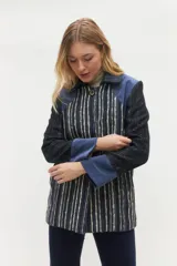 Tapado midi con diseño de combinación de texturas, presenta paneles frontales a rayas verticales en tonos azul, blanco y negro, con detalles en gamuza azul en hombros y puños. Incluye cierre frontal con botones grandes y cuello clásico.