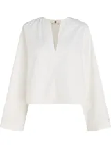 Camisa blanca de algodón con cuello en V y mangas largas acampanadas.