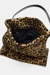 Bolso de hombro confeccionado en piel con estampado animal print de leopardo y textura. Cuenta con compartimento interior con cremallera, asa larga de hombro y cierre mediante botón imantado.