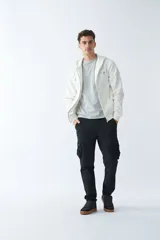 Campera de felpa color blanco hueso, con capucha y cordón ajustable, cierre frontal con cremallera, bolsillos laterales, logo y arte estampado en el pecho.