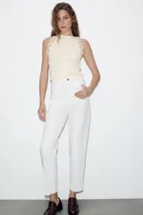 Top sin mangas de tejido rib color crema, con cuello redondo y detalle de encaje en los hombros.