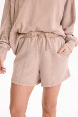 Short de felpa sin frisa con efecto acid wash color tostado, bolsillos laterales, tiro medio-alto, cintura elástica con cordón ajustable y costuras decorativas delanteras.