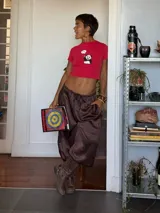 Pantalón de corte holgado y tiro alto, confeccionado en tela satinada color marrón oscuro. Presenta cintura elástica con cordón ajustable y diseño amplio en las piernas.