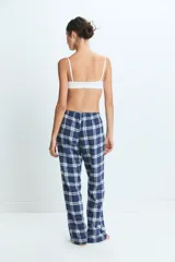 Pantalon de pijama con estampado de cuadros en tonos azul, blanco y rojo, con cintura elástica y corte holgado.